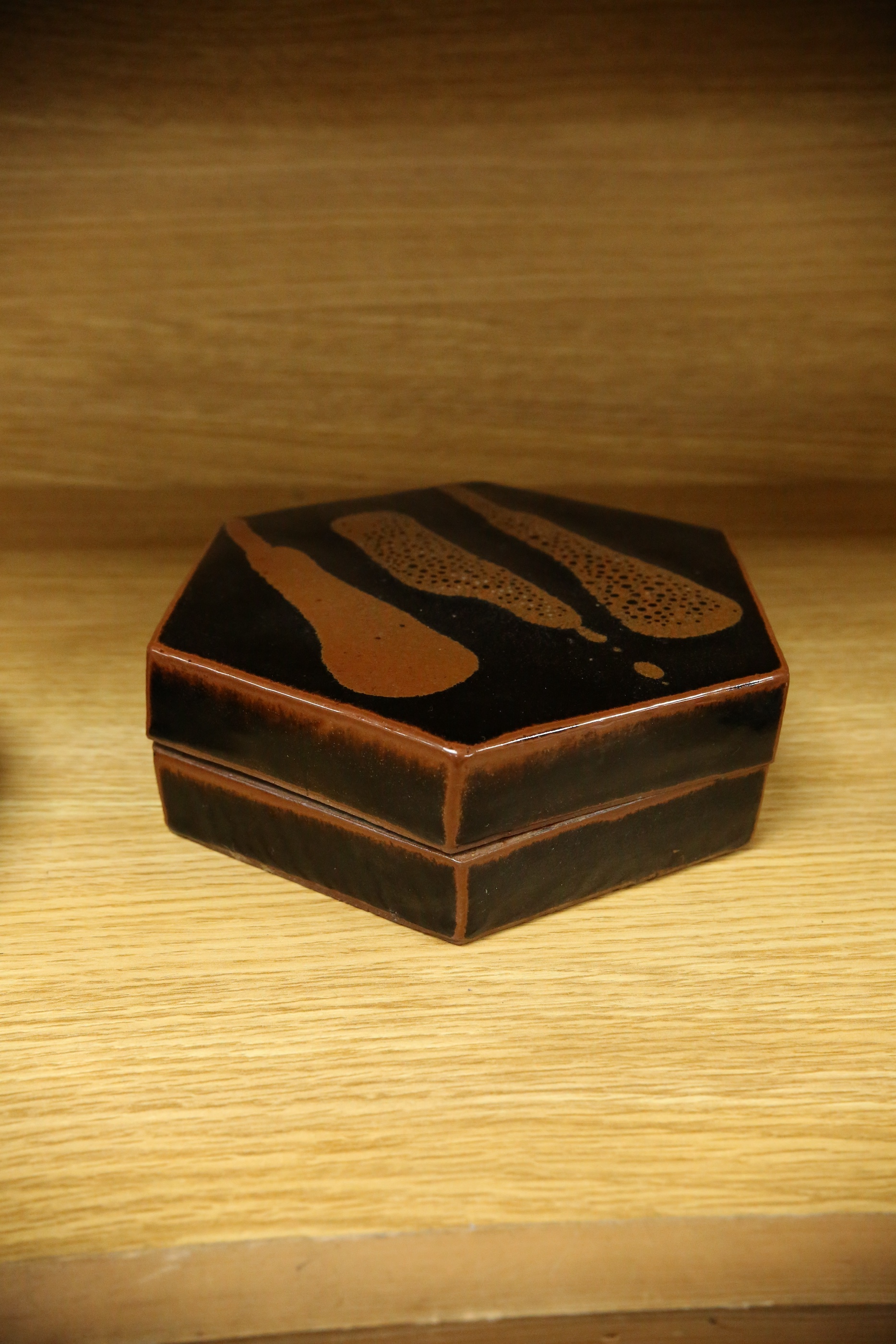 A Japanese studio tenmoku glazed hexagonal box and cover, unmarked, 18cm wide. Condition - good